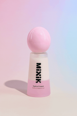 Shaking the pink MIXIK Hydra Cream bottle to mix the cream layer and rosewater layer